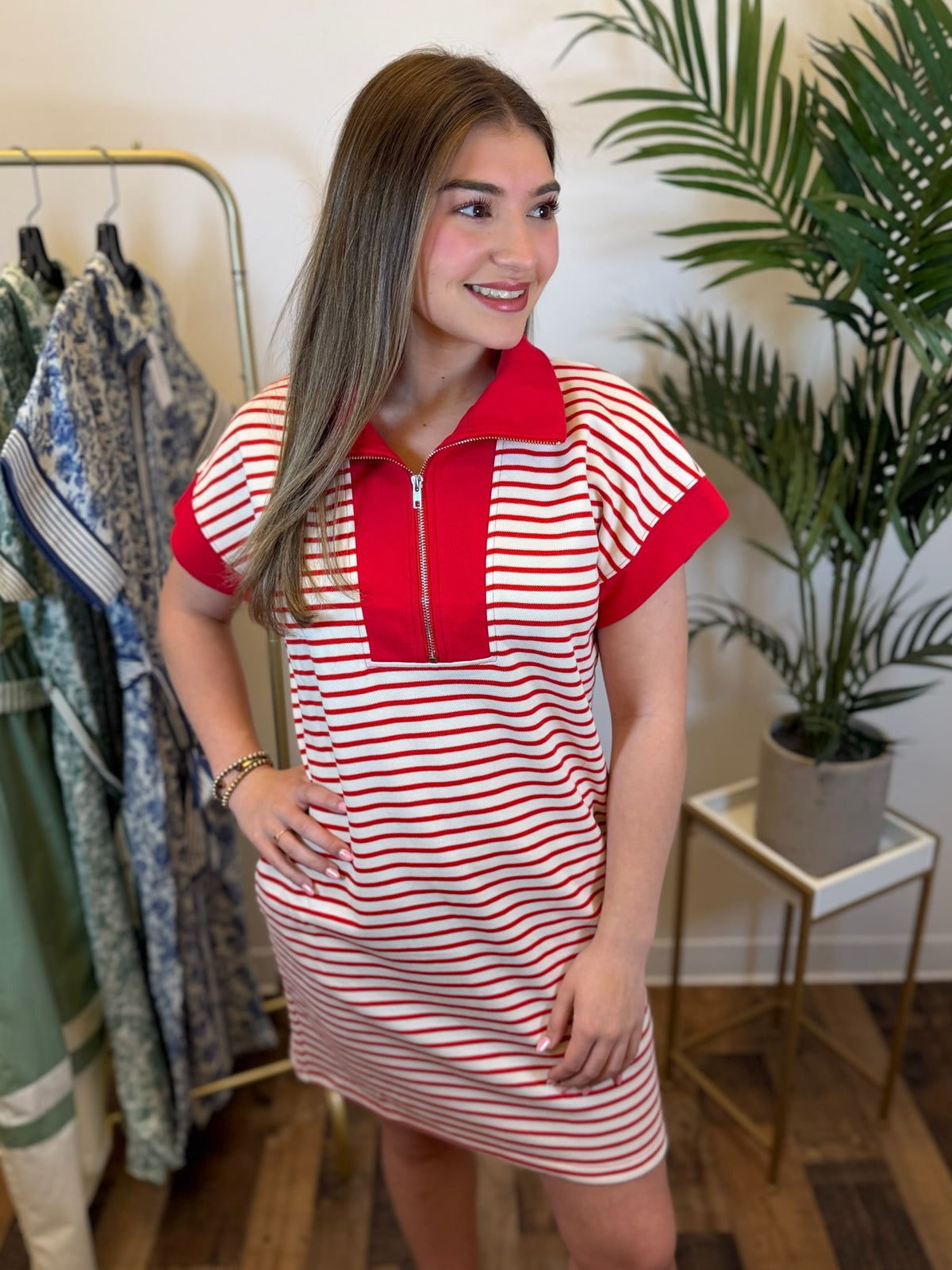 Woman wearing a red and white striped short sleeve dress with red contrast trim in a clothing store.