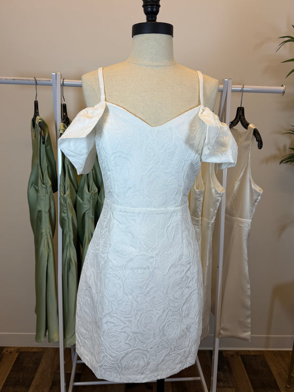 White mini dress with floral texture on a mannequin with a blurred indoor background