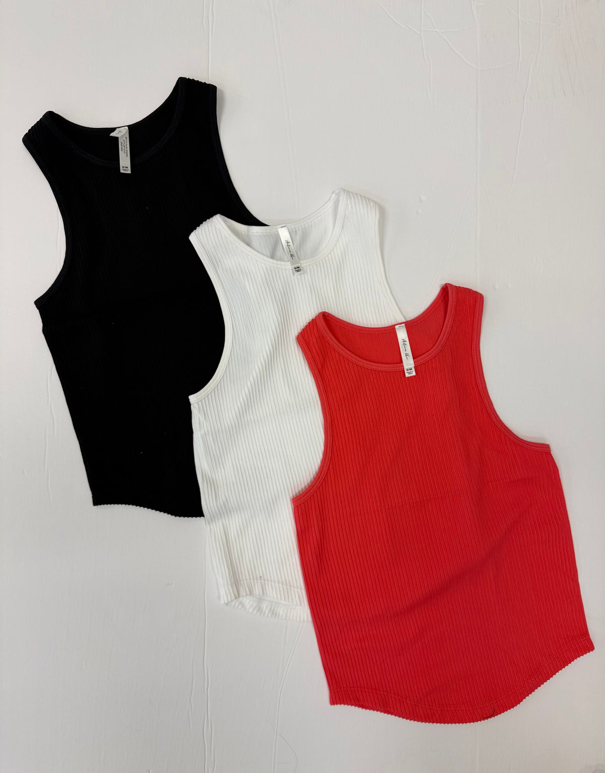 Black, white, and red sleeveless racerback tank tops on a white background