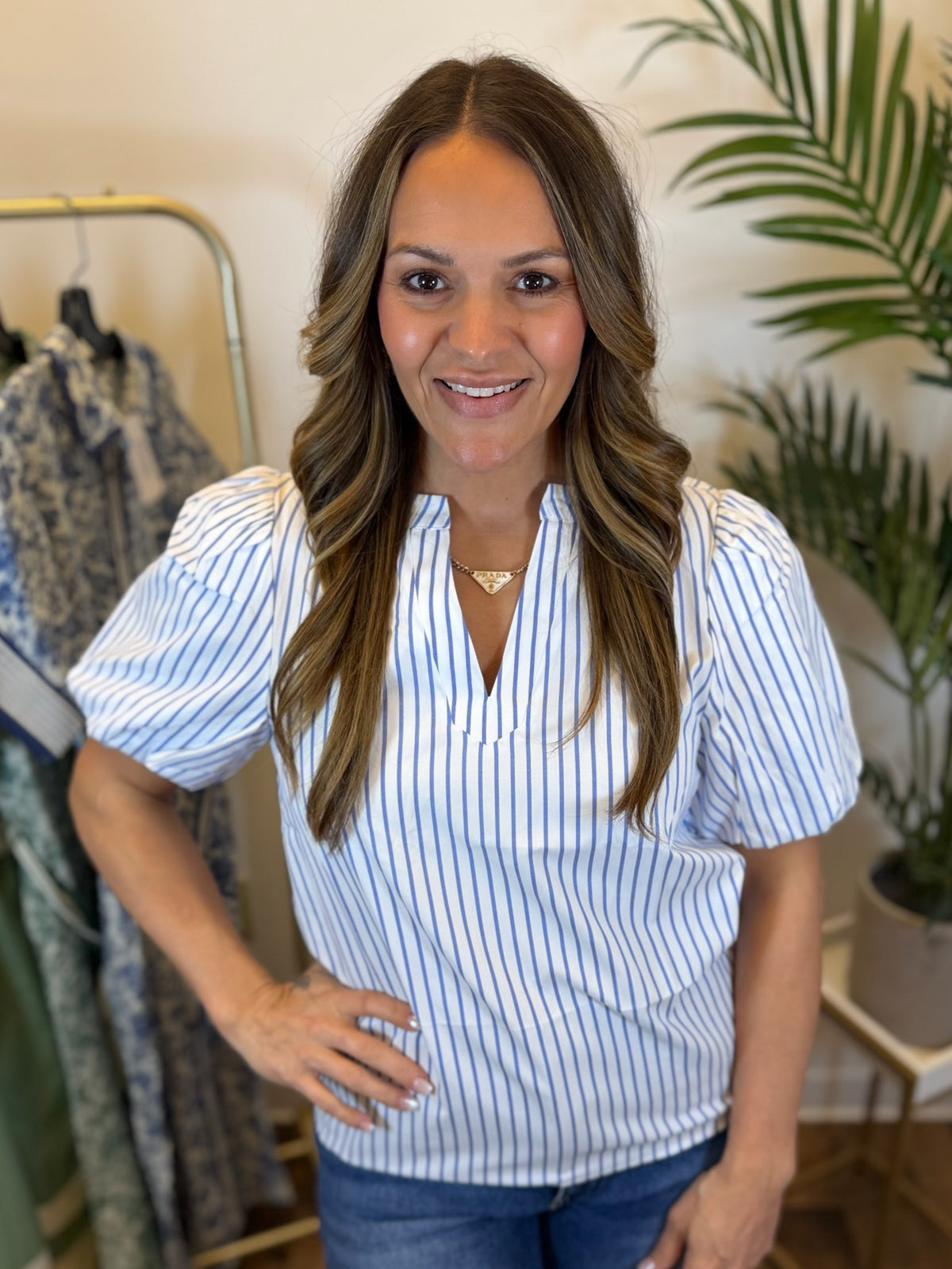 Woman wearing a white and blue blouse with short puff sleeves in a clothing store.