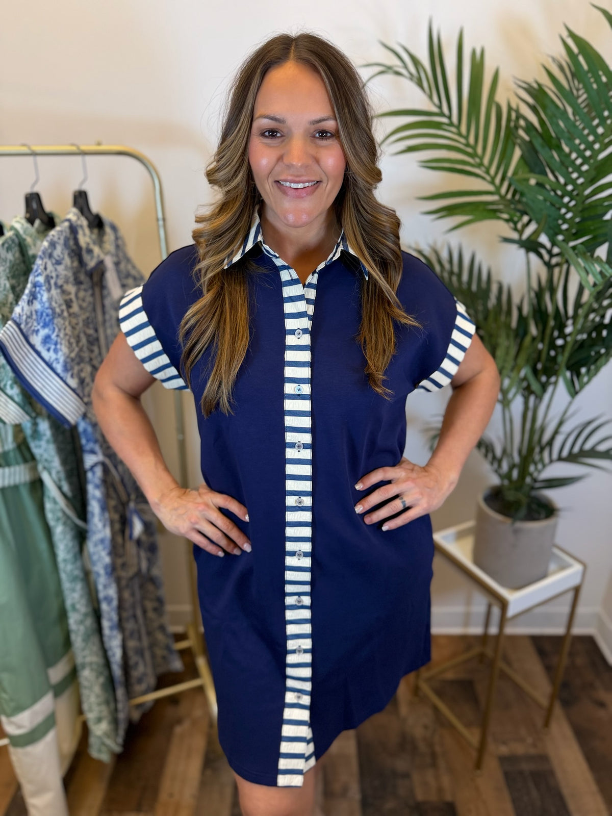 Woman wearing a navy dress with white striped contrast trim details in a clothing store.