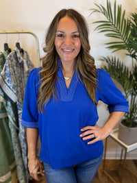 Woman wearing a blue top with 3/4 length sleeves in a clothing store setting