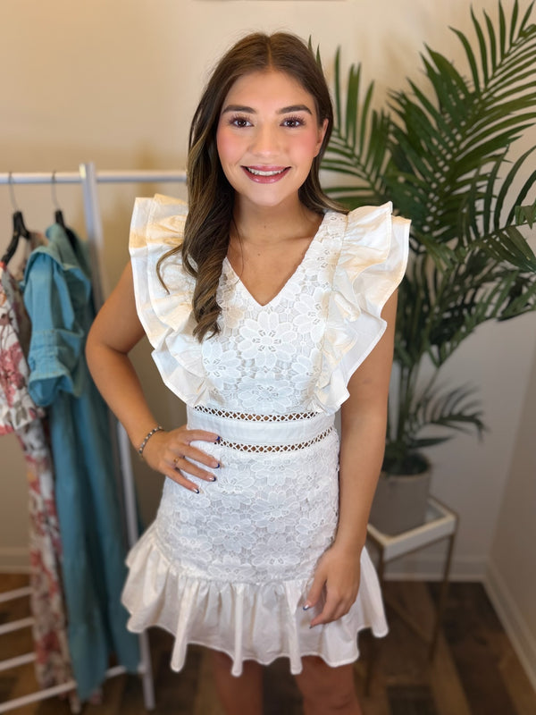 Woman wearing a white lace v-neck dress in a clothing store setting
