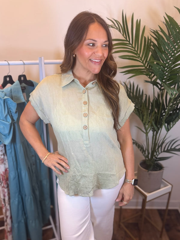 Woman wearing light sage short sleeve top with ribbing, button neck, and collar.