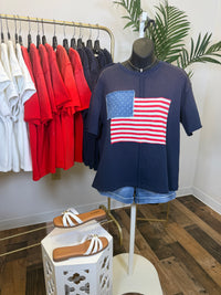 Navy blue vintage wash t-shirt with American flag design on a mannequin, surrounded by colorful shirts on hangers.