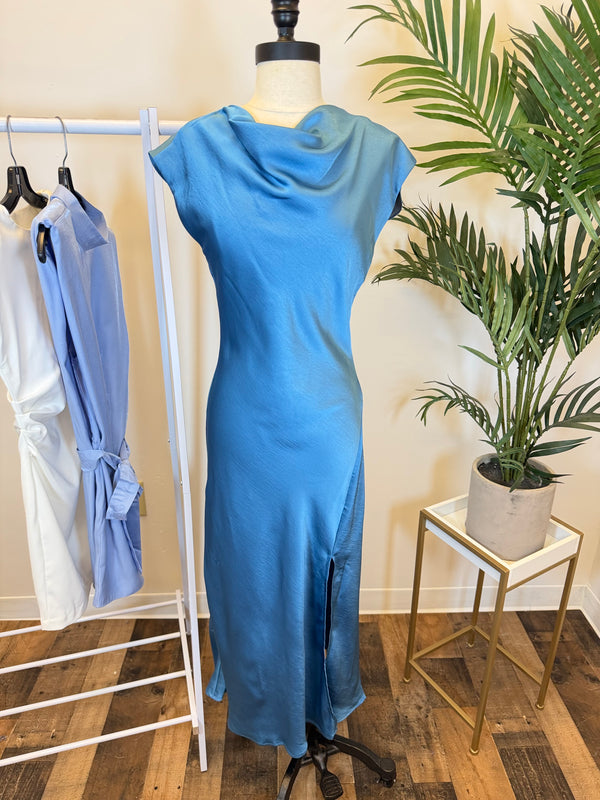 Blue short sleeve midi dress with draped neckline and side slit on a mannequin in a clothing store setting.