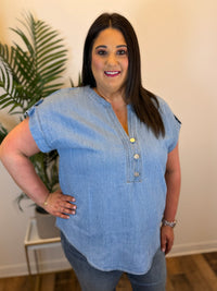 Woman wearing a blue denim top with a plant in the background