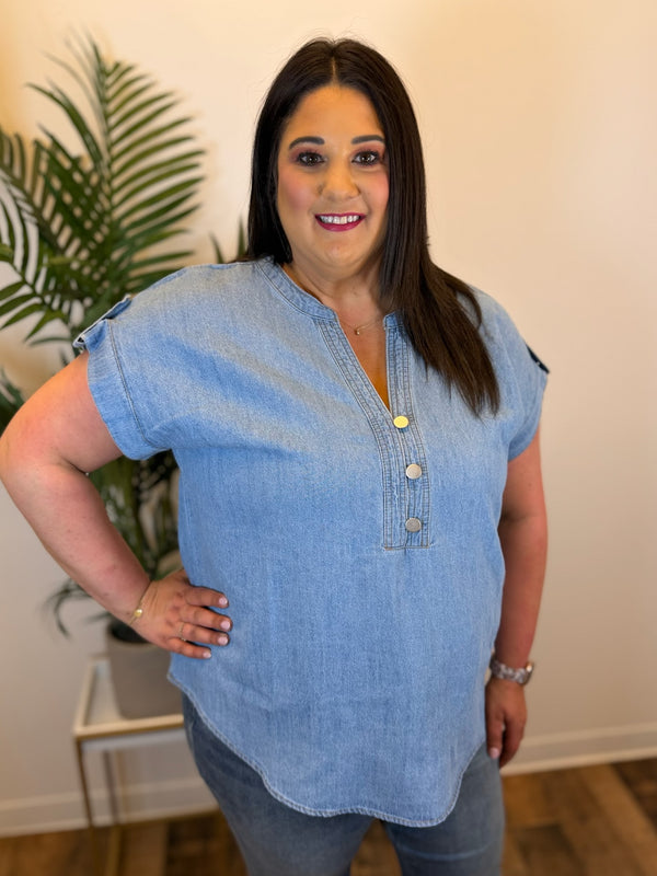 Woman wearing a blue denim top with a plant in the background