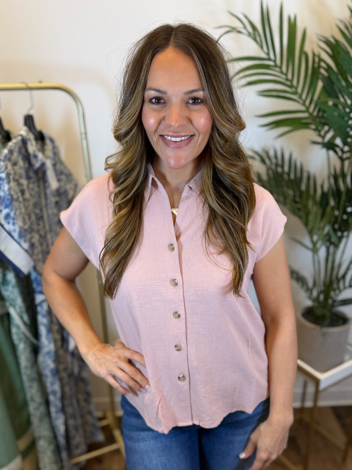 Woman wearing a pink button front blouse in a clothing store setting