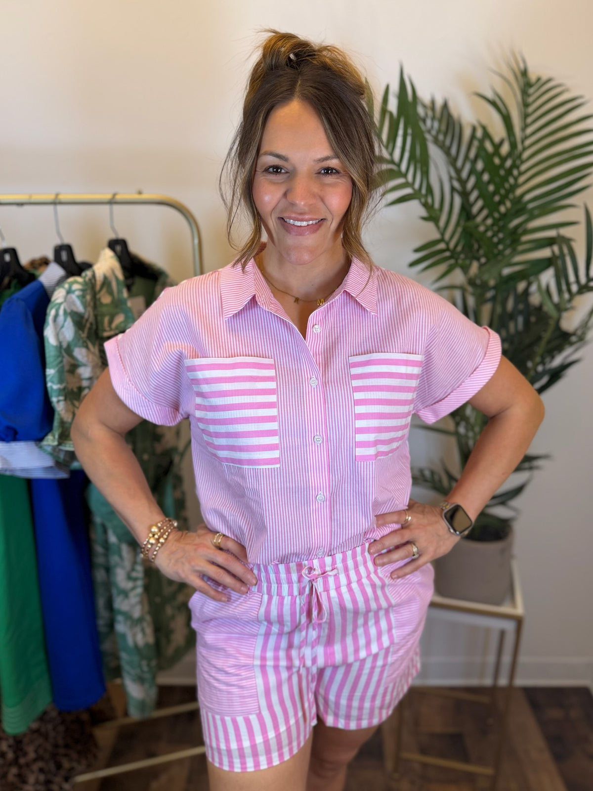 Woman wearing a pink and white striped outfit in a clothing store.