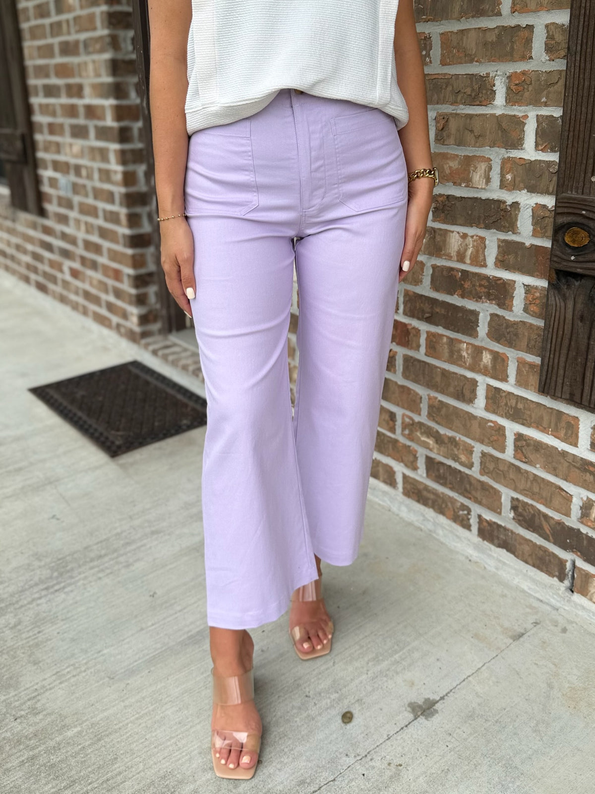 Person wearing lavender wide leg pants standing against a brick wall.