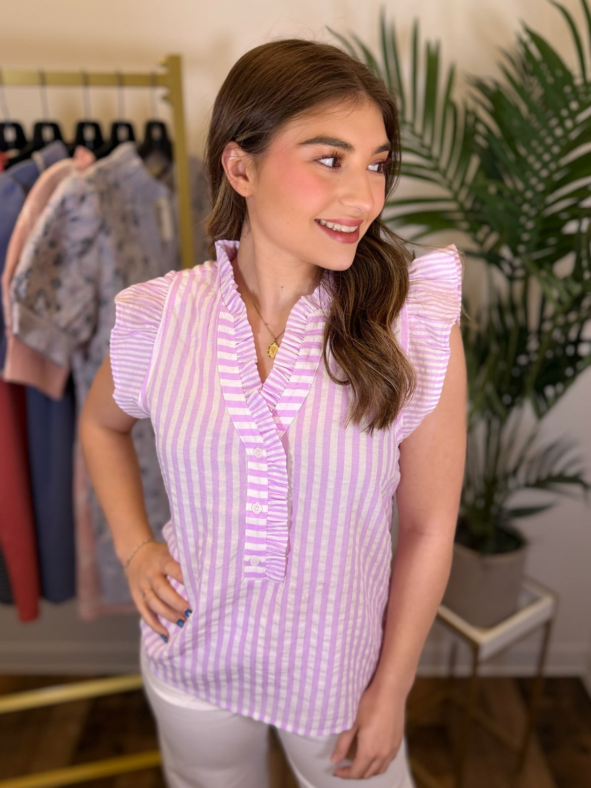 Woman wearing a purple and white striped blouse in a clothing store.