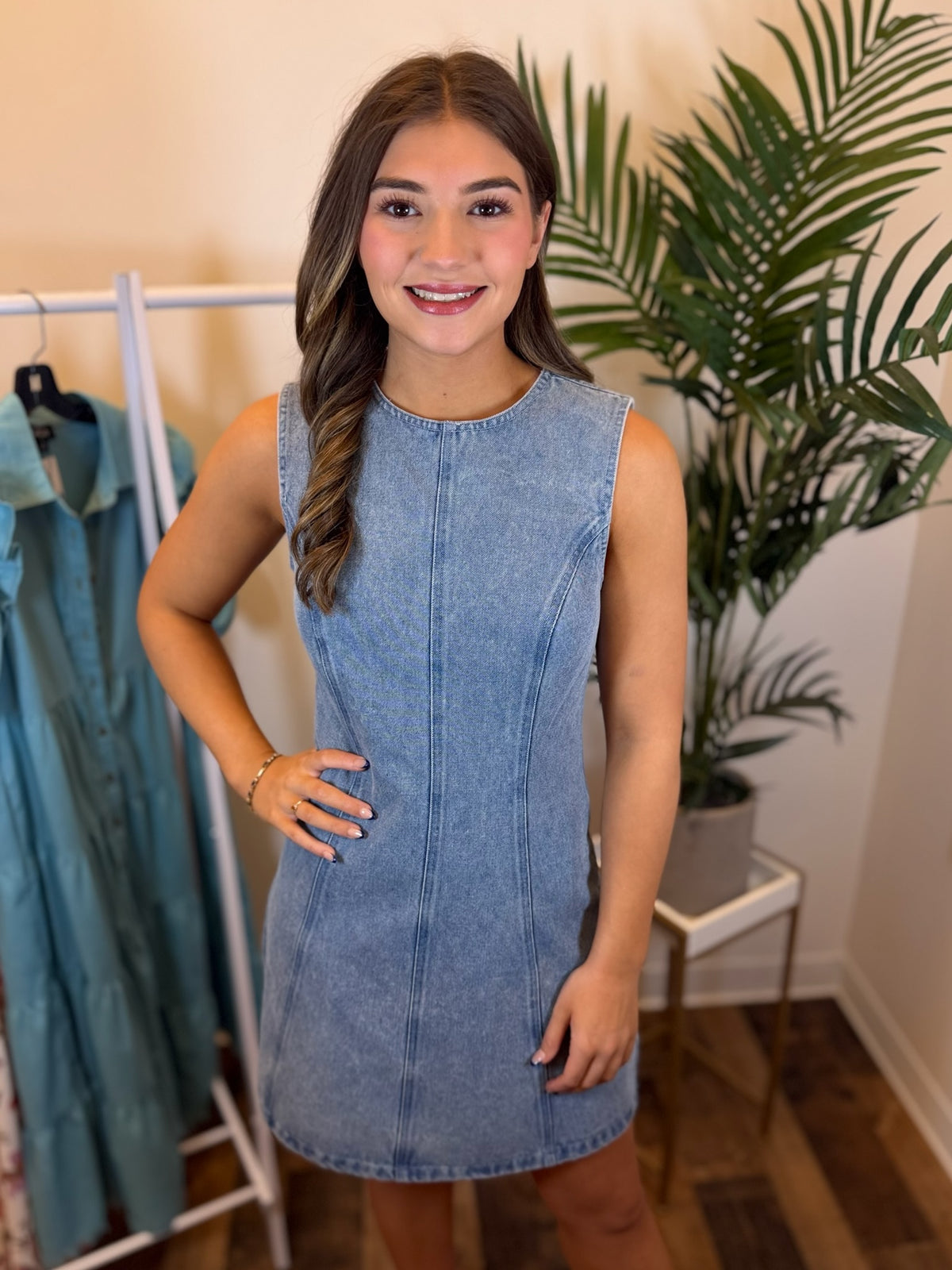 Woman wearing a light wash denim dress in a clothing store setting.