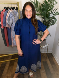 Woman wearing a blue dress with a patterned hem in a clothing store.