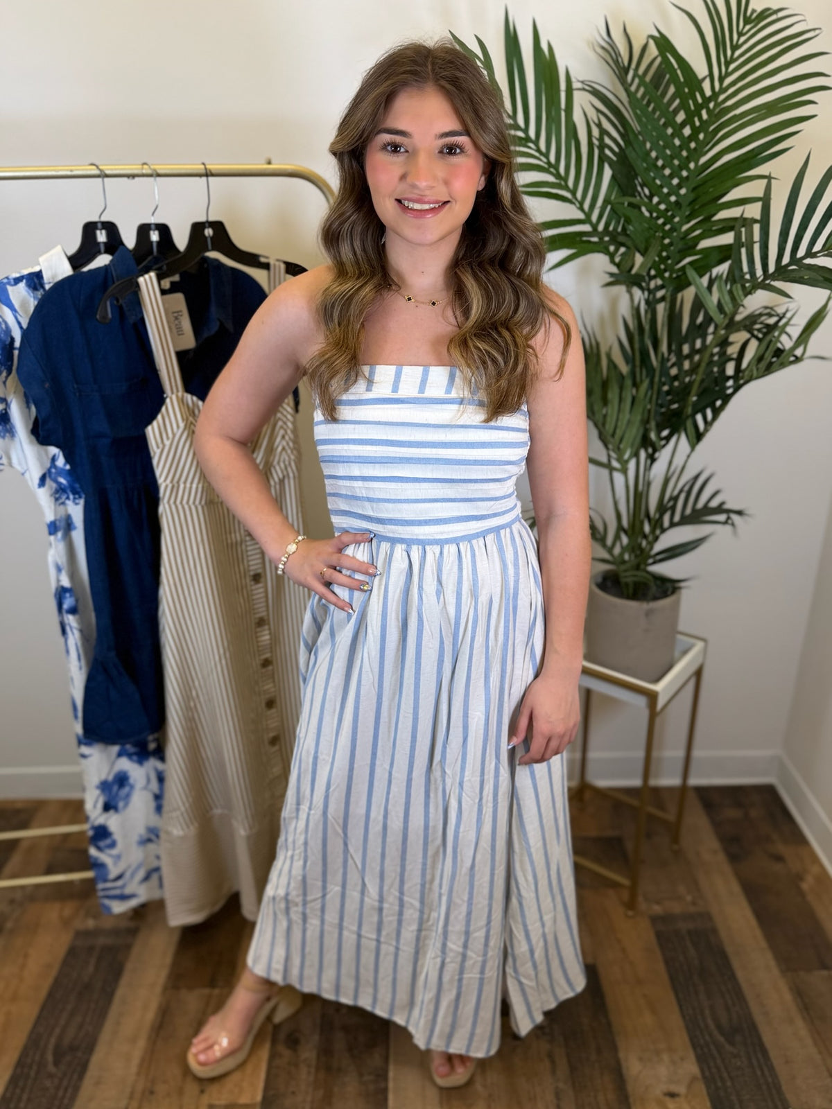 Woman wearing a strapless blue and white striped dress in a clothing store.