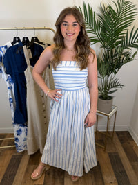 Woman wearing a strapless blue and white striped dress in a clothing store.