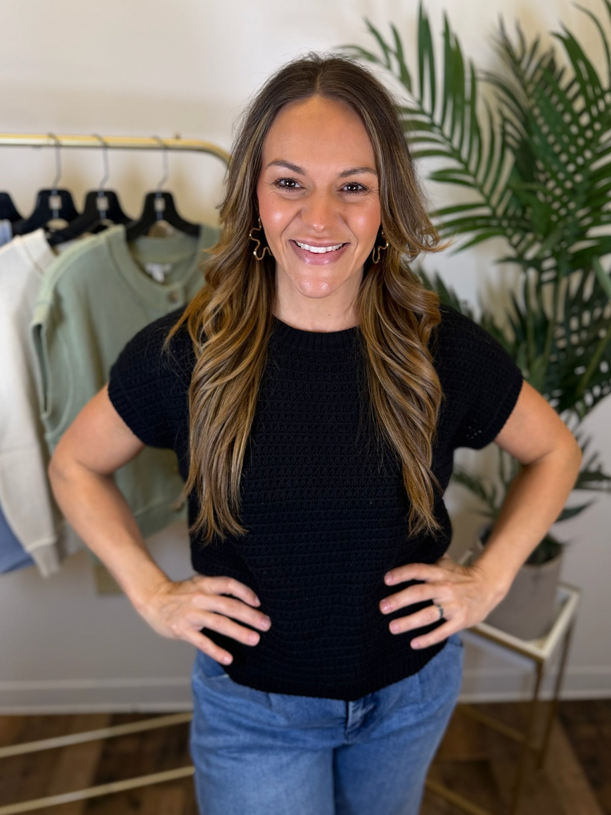 Woman wearing a short sleeve black top and blue jeans standing in a clothing store.