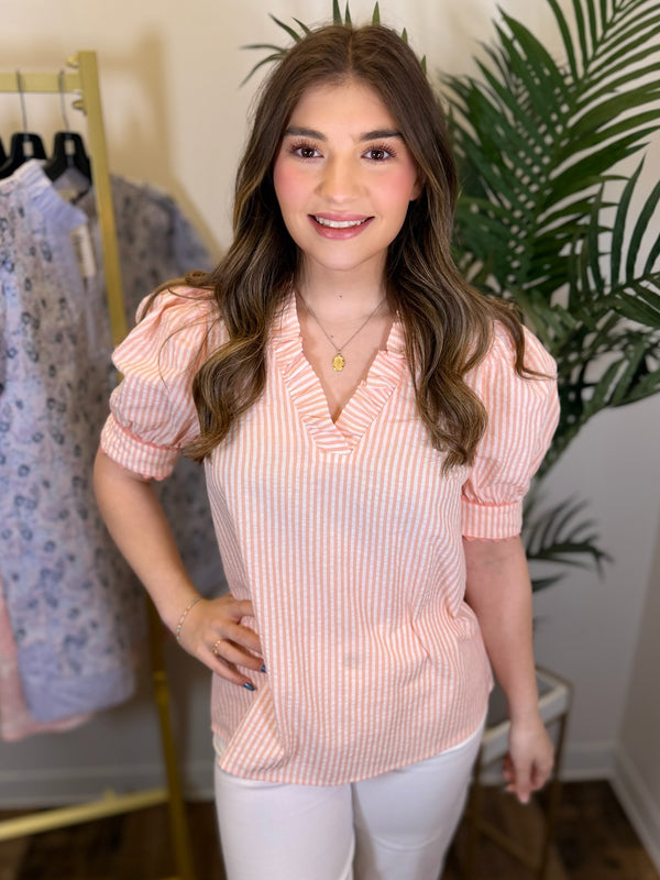 Woman wearing a pink striped blouse in a clothing store setting