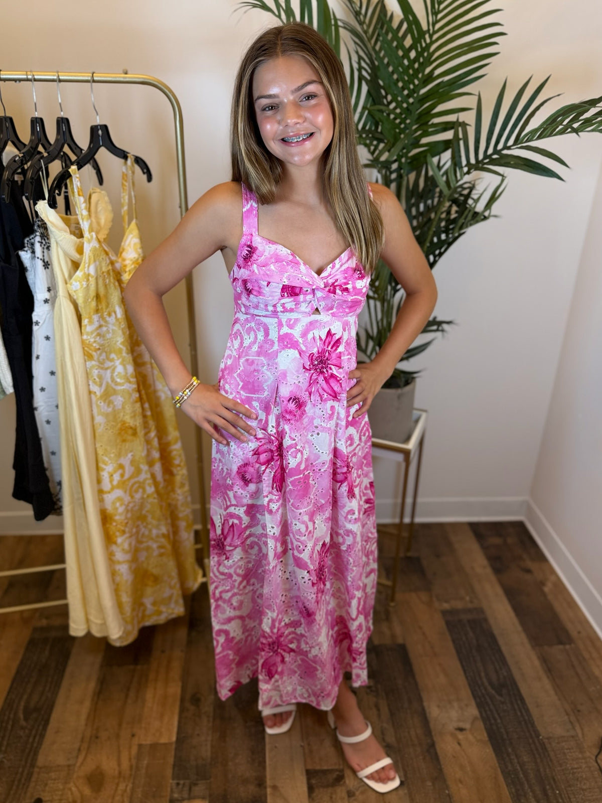 Woman wearing a pink floral dress in a clothing store.