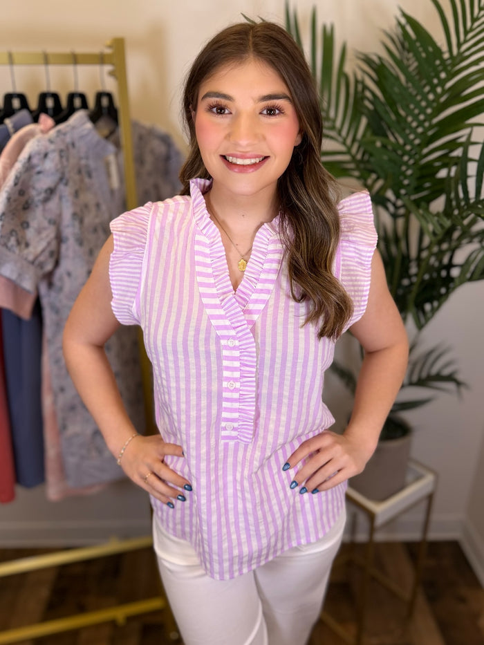 Woman wearing a purple striped shirt in a clothing store setting