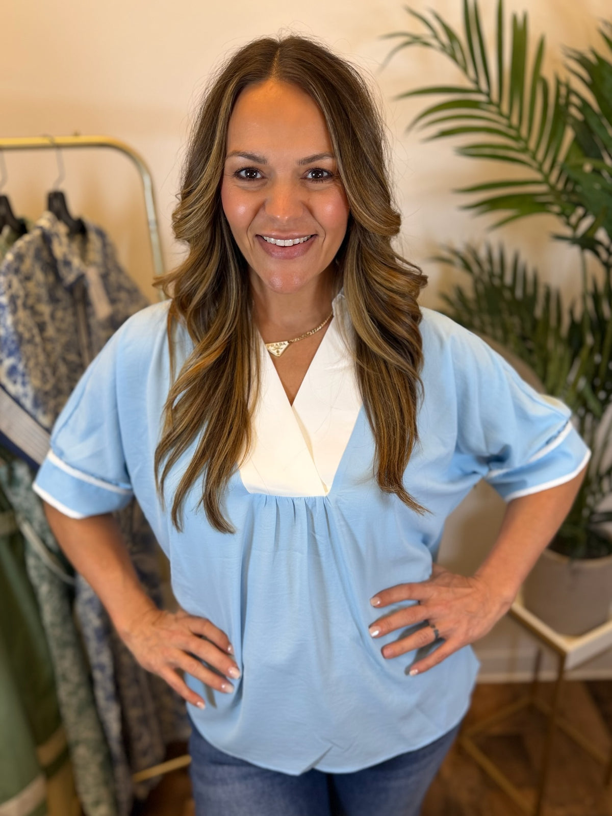 Woman wearing a light blue blouse with short sleeves and a white collar in a clothing store.