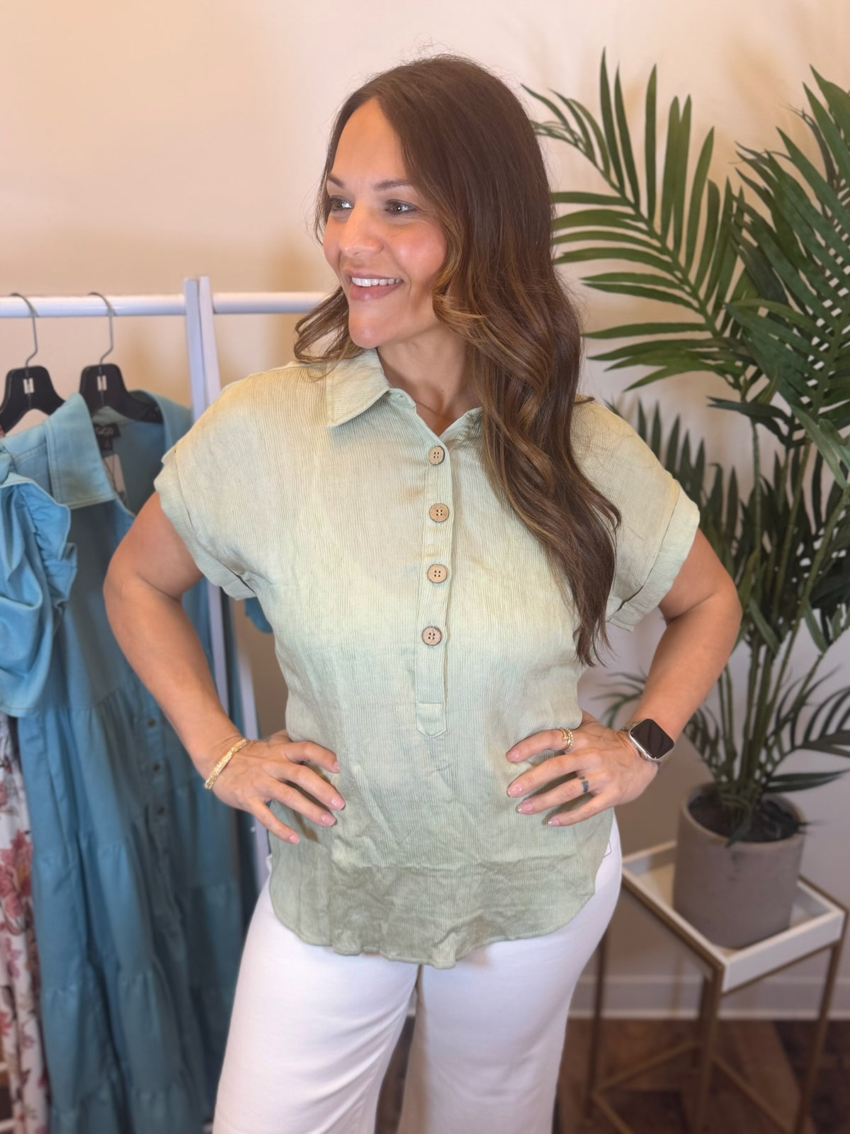 Woman wearing short sleeve sage top with collar neckline.