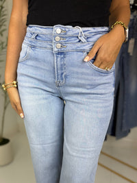 Close up of light blue jeans with triple button waistband worn by a person with a blurred background