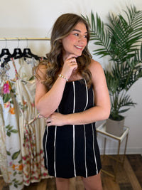 Woman wearing a black dress with cream stripes in a clothing store.