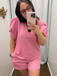 Woman taking mirror selfie wearing matching Pink puff sleeve top and shorts.