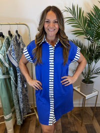 Woman wearing a blue button front dress with white stripes in a clothing store.