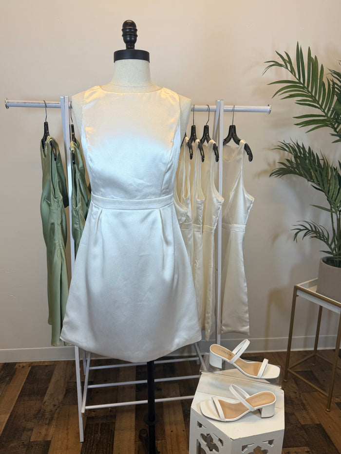 Sleeveless White dress with boat neck on a mannequin with shoes and other dresses in the background