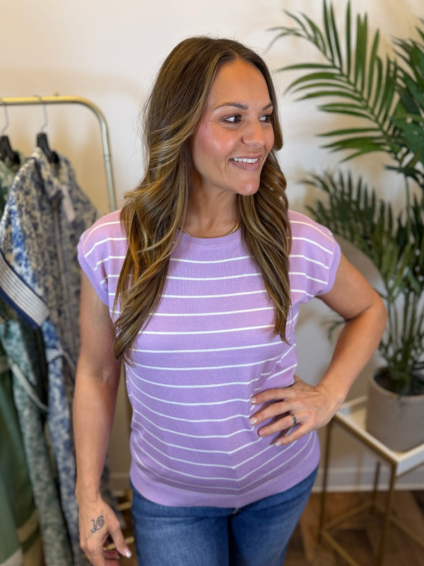 Woman wearing a purple striped shirt with short sleeves and crew neck in a clothing store setting