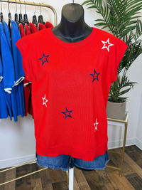 Red top with star patterns on a mannequin in a store setting.