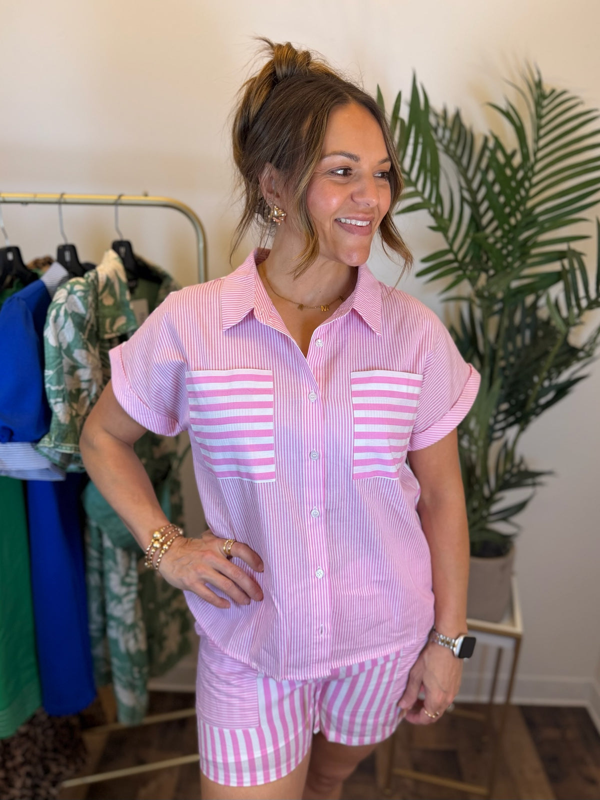 Woman wearing a pink and white striped outfit in a clothing store.