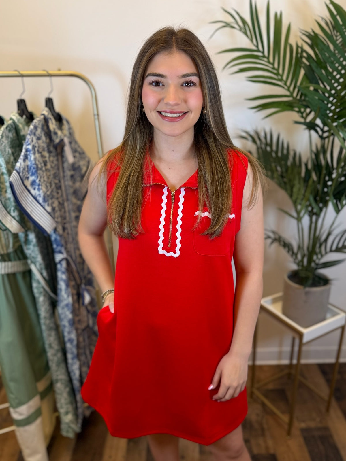 Woman wearing a red dress with white trim in a clothing store.