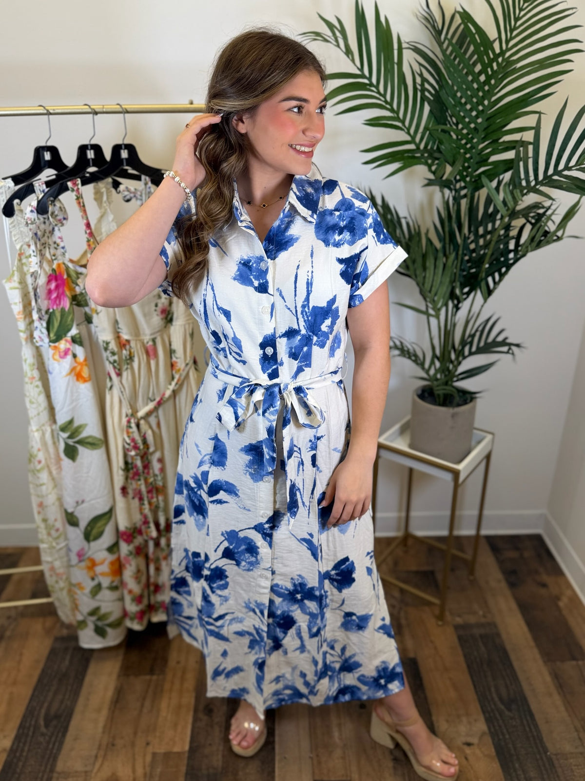 Woman wearing a blue floral dress in a clothing store.