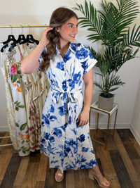 Woman wearing a blue floral dress in a clothing store.