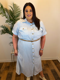 Woman wearing a light blue denim dress with gold buttons indoors.