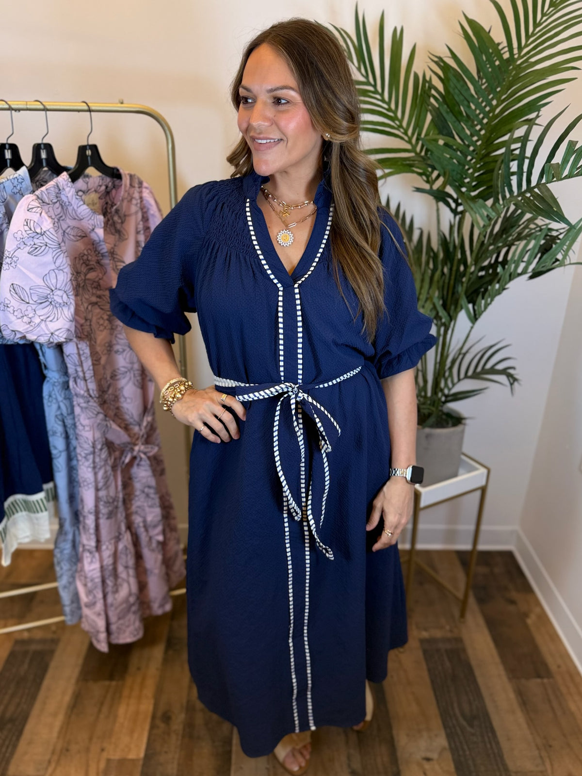 Woman wearing a navy dress with split neckline and puff sleeves in a clothing store.