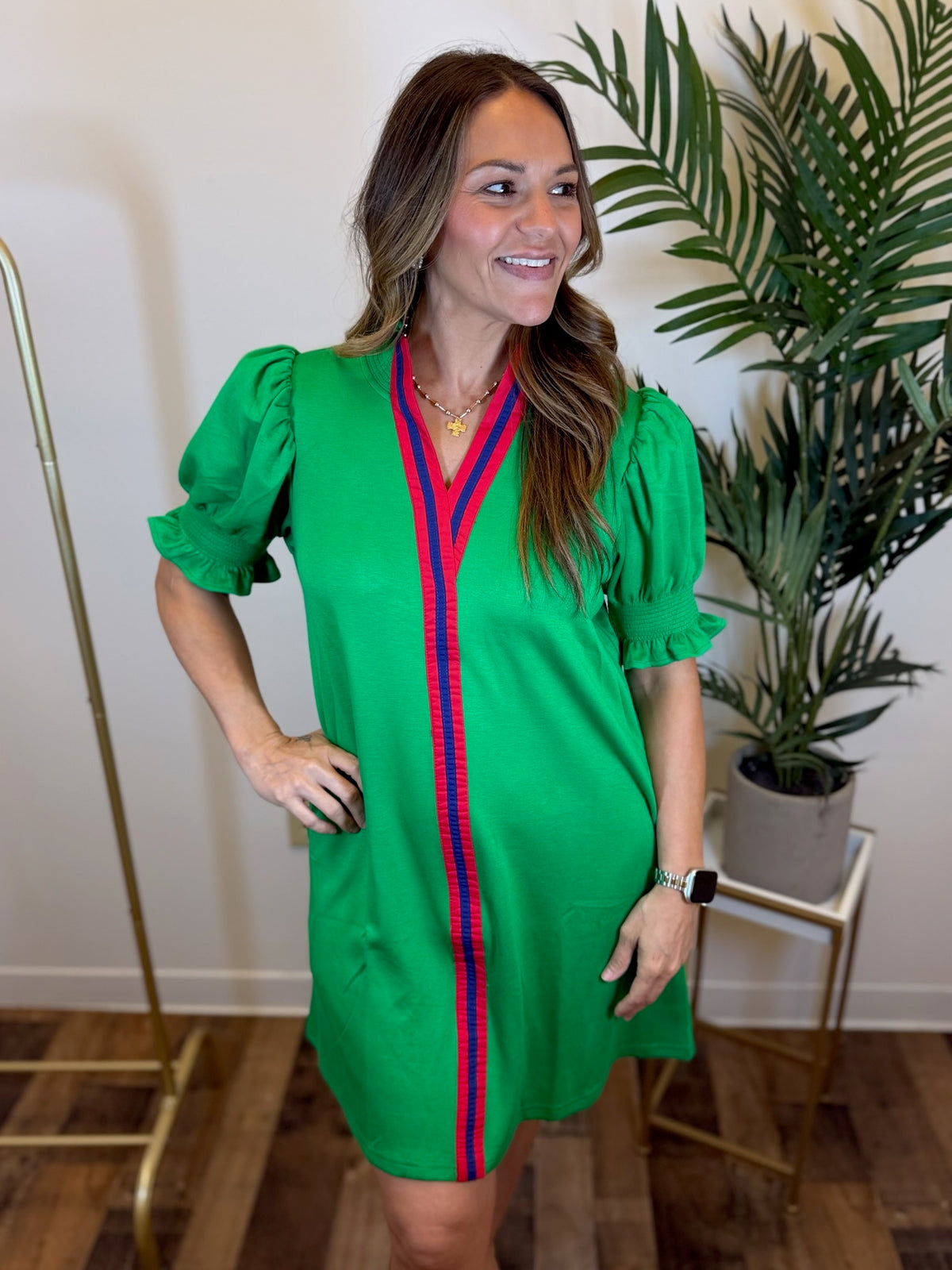 Woman wearing a green dress with red and blue stripes indoors.