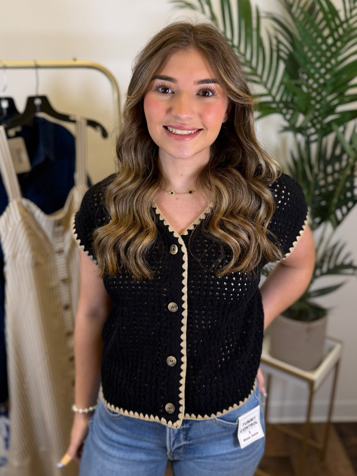 Woman wearing a black and tan short sleeve button front cardigan in a clothing store setting