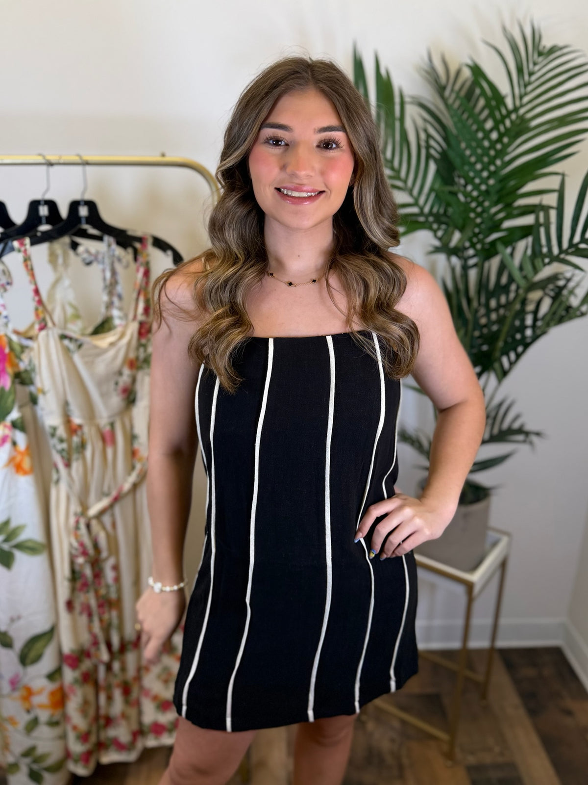 Woman wearing a black dress with cream stripes in a clothing store.
