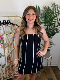 Woman wearing a black dress with cream stripes in a clothing store.