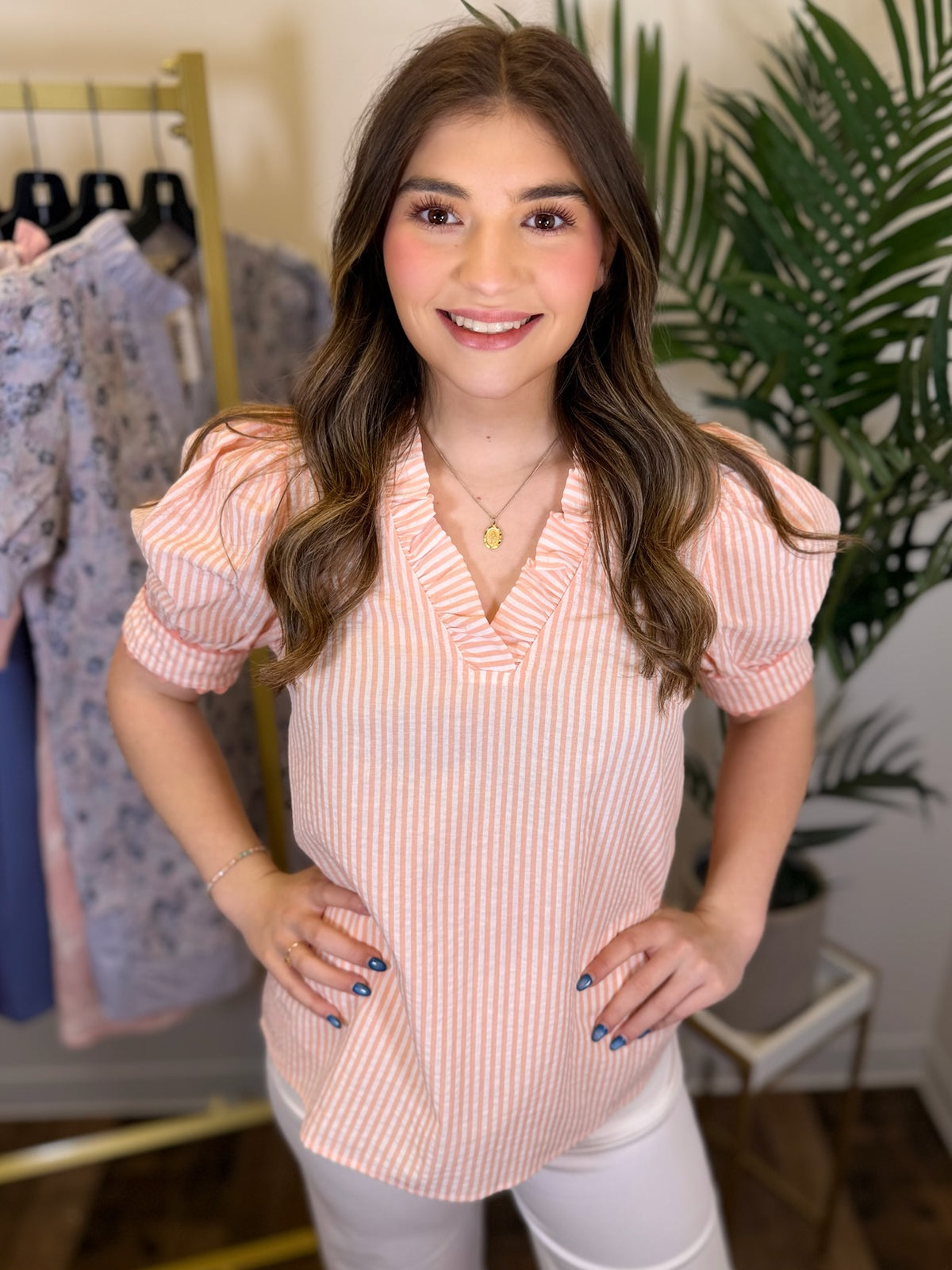 Woman wearing a pink striped blouse in a clothing store setting