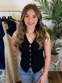 Woman wearing a black vest with gold buttons in a clothing store setting
