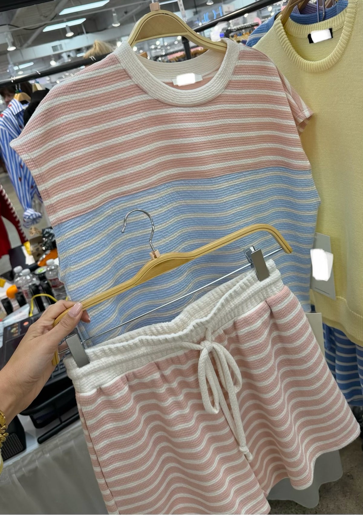 Pink and blue matching striped shirt and shorts set on hangers in a store setting