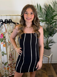 Woman wearing a black and cream striped mini dress in a clothing store.