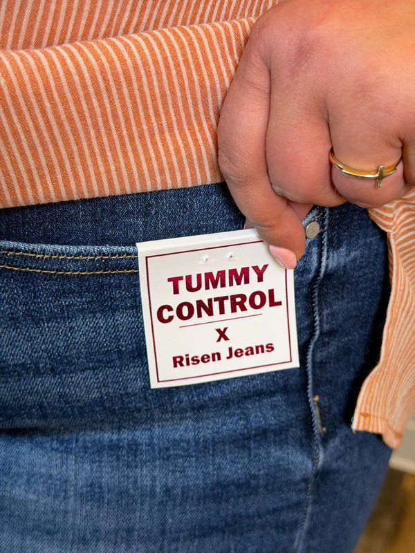 Person wearing blue jeans with a 'Tummy Control x Risen Jeans' label.