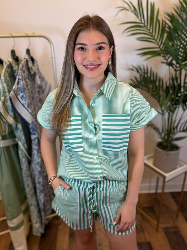 Woman wearing a matching green and white striped outfit in a clothing store.