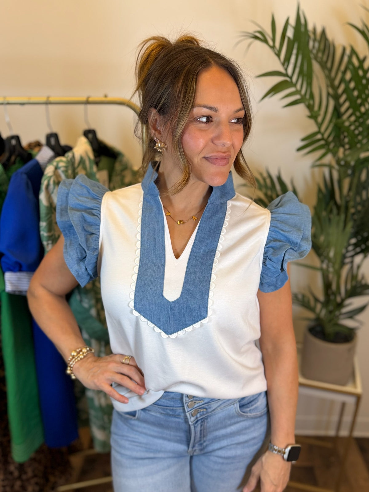 Woman wearing a white blouse with blue accents in a clothing store.